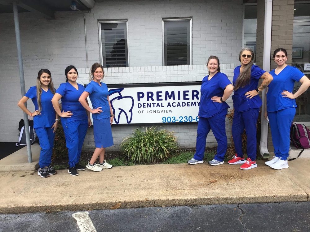 Premier Dental Academy students gathered by the school sign at the Longview campus